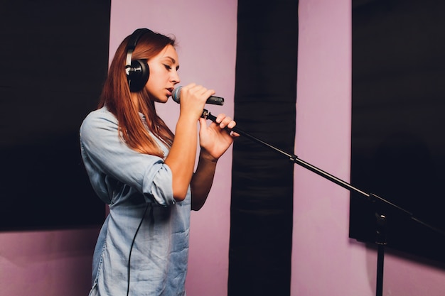 Student practicing vocal exercises with trained singing coach in modern music studio